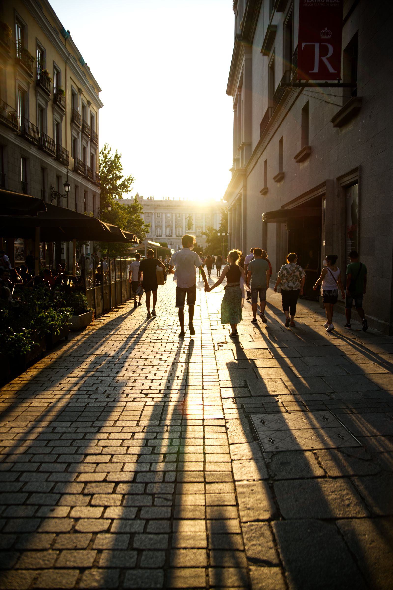 People walking through a city street in low evening sun