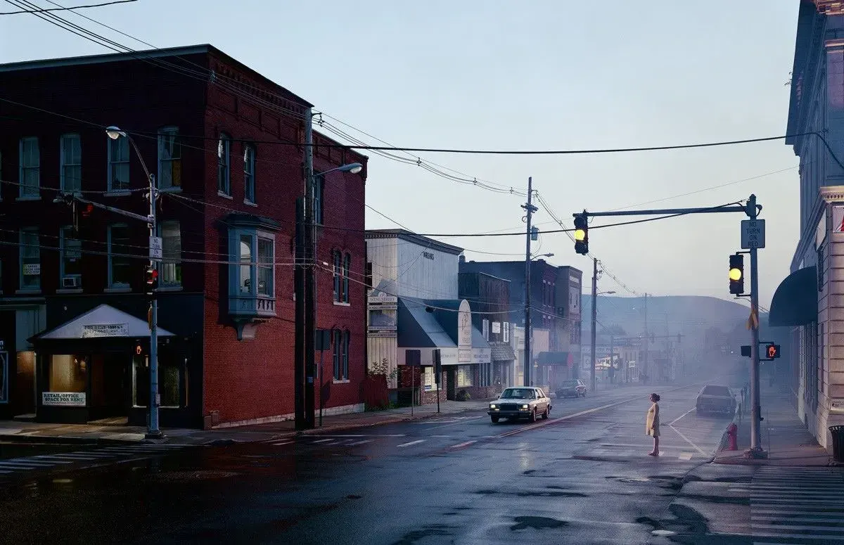 Gregory Crewdson's Untitled Merchants Row, showing a lone pedestrian at a wet and misty small-town intersection